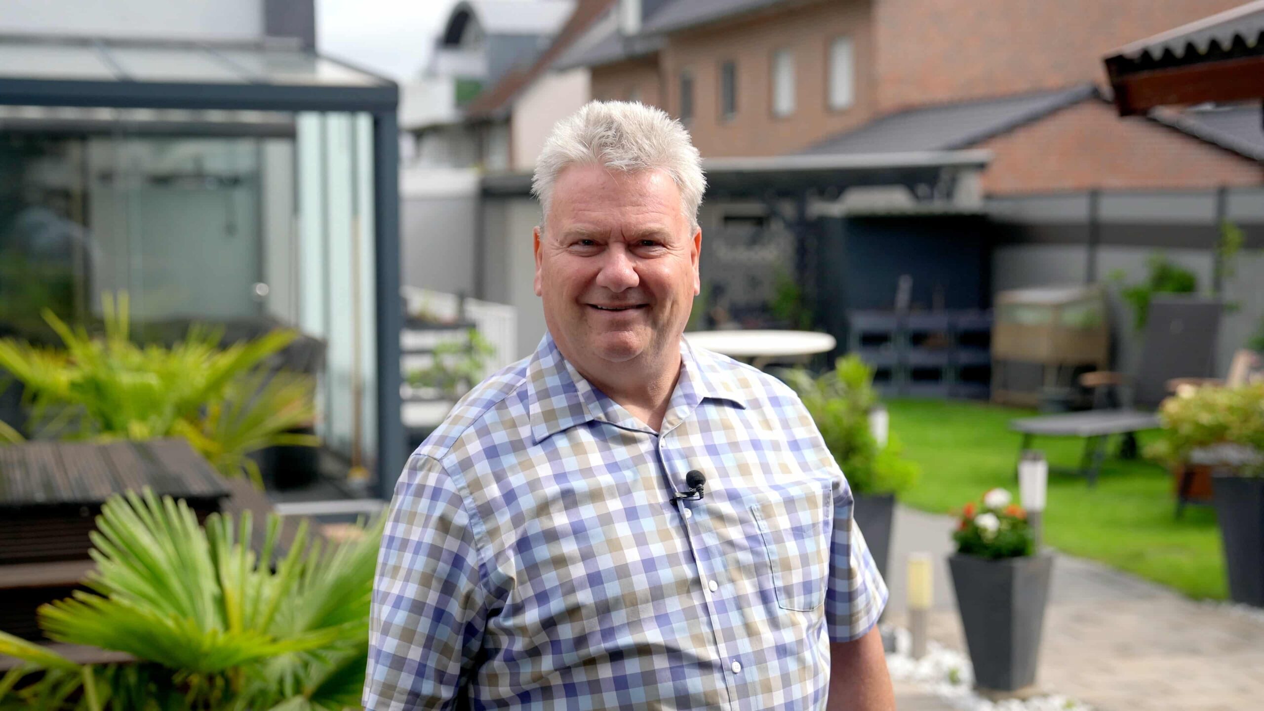 Lächelnder Mann im karierten Hemd im Garten