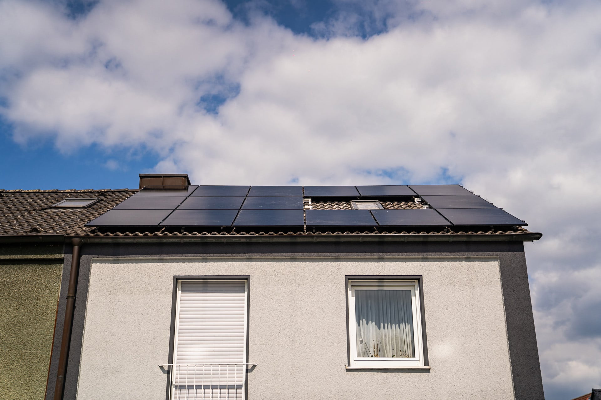 Hausdach mit Solarpanelen unter blauem Himmel