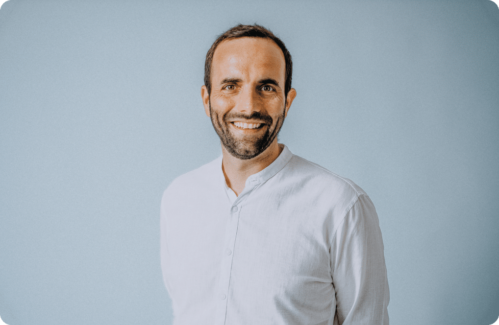 Lächelnder Mann in weißem Hemd vor blauem Hintergrund